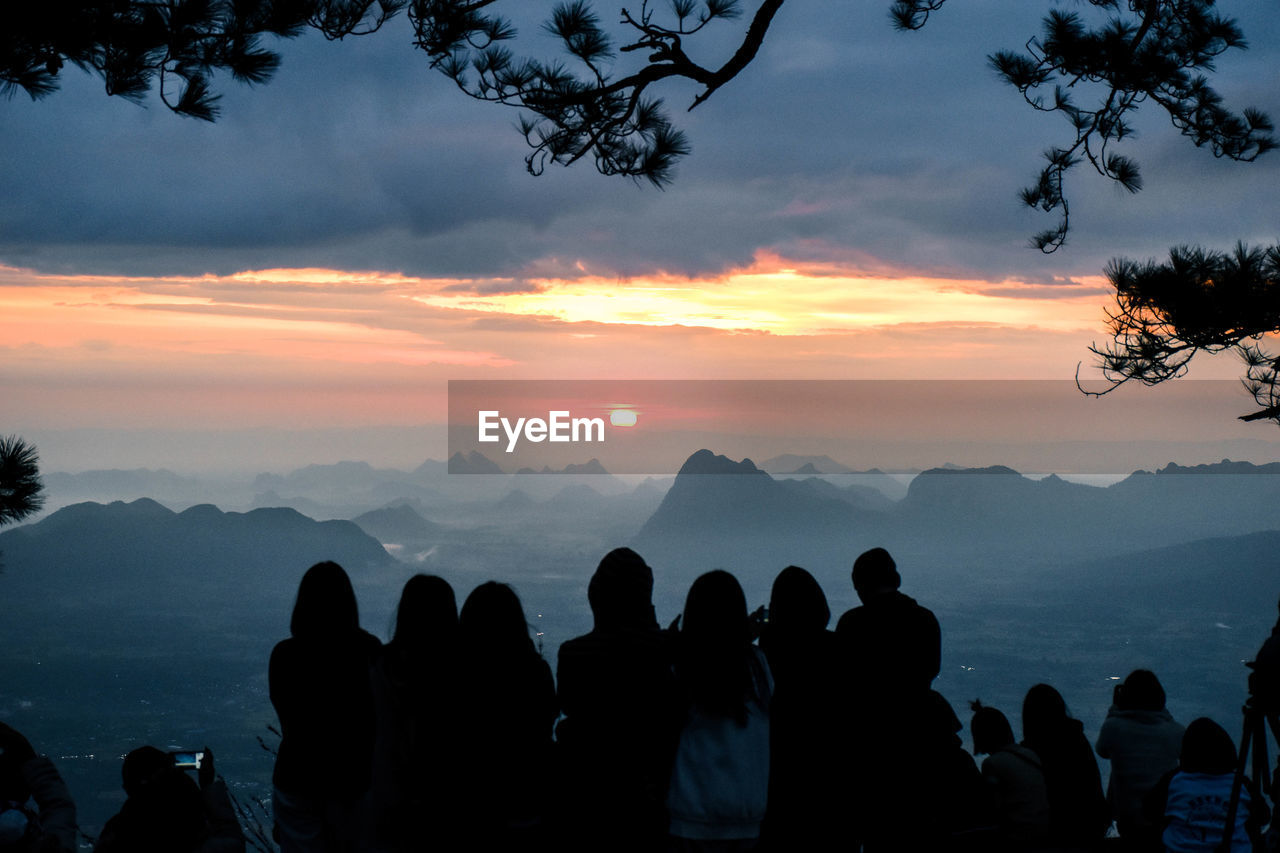 Silhouette people looking at mountains against sky during sunset