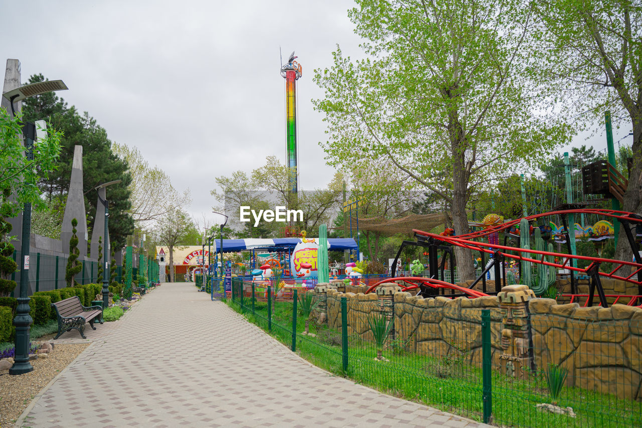 park, plant, tree, city, architecture, playground, nature, sky, walkway, public space, built structure, amusement park, day, park - man made space, recreation, no people, outdoors, flag, travel destinations, building exterior, footpath, cloud, multi colored, street