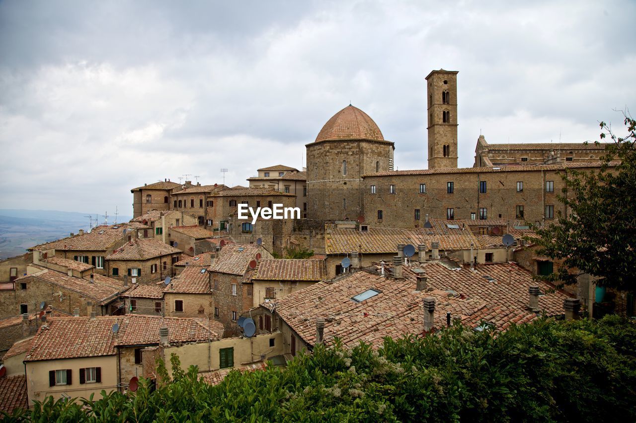 Buildings in town against cloudy sky