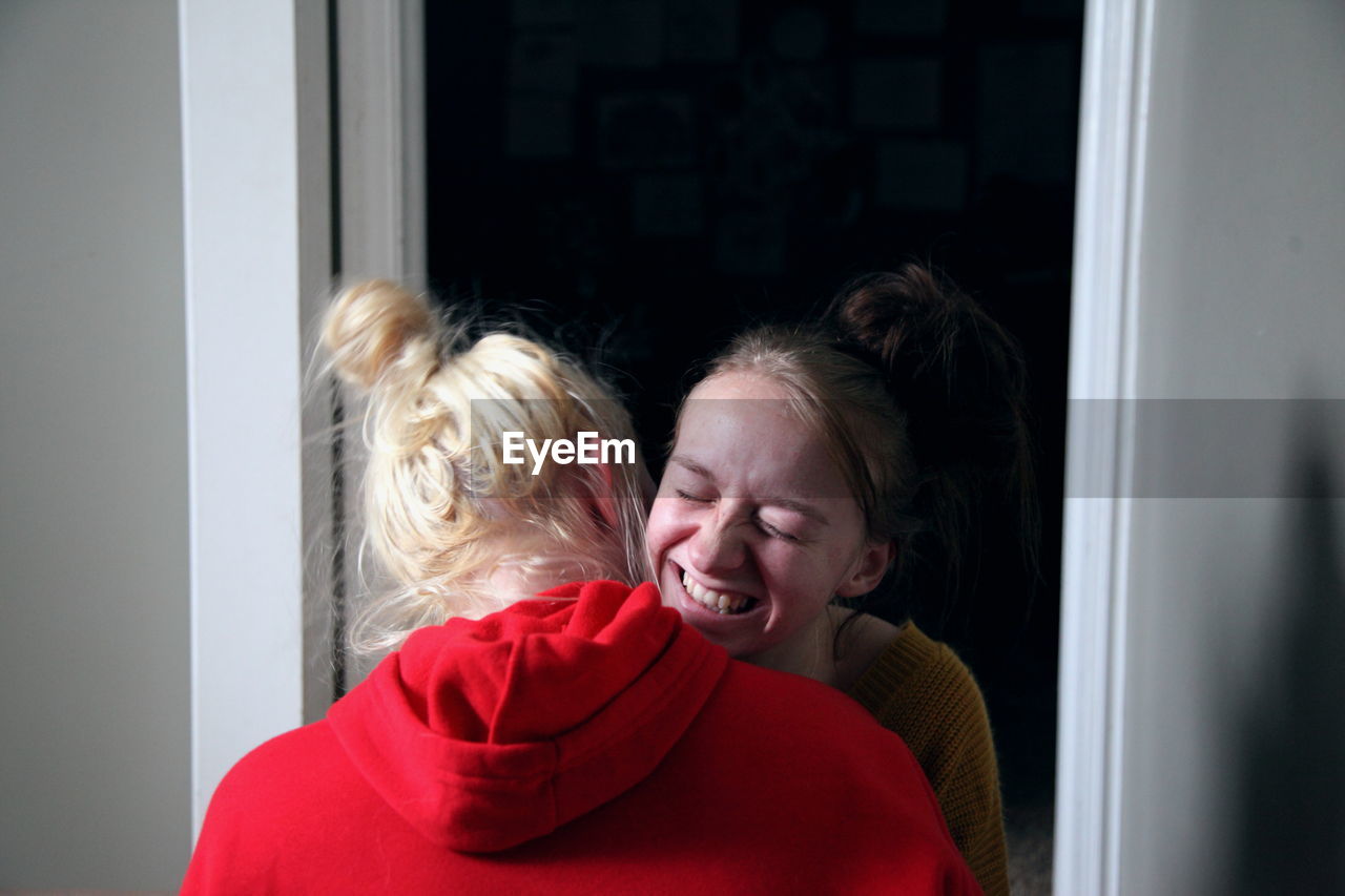 Smiling lesbian woman embracing girlfriend at home