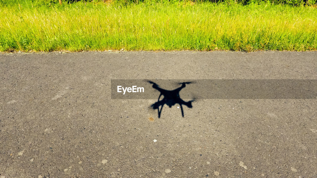 High angle view of drone shadow on road during sunny day