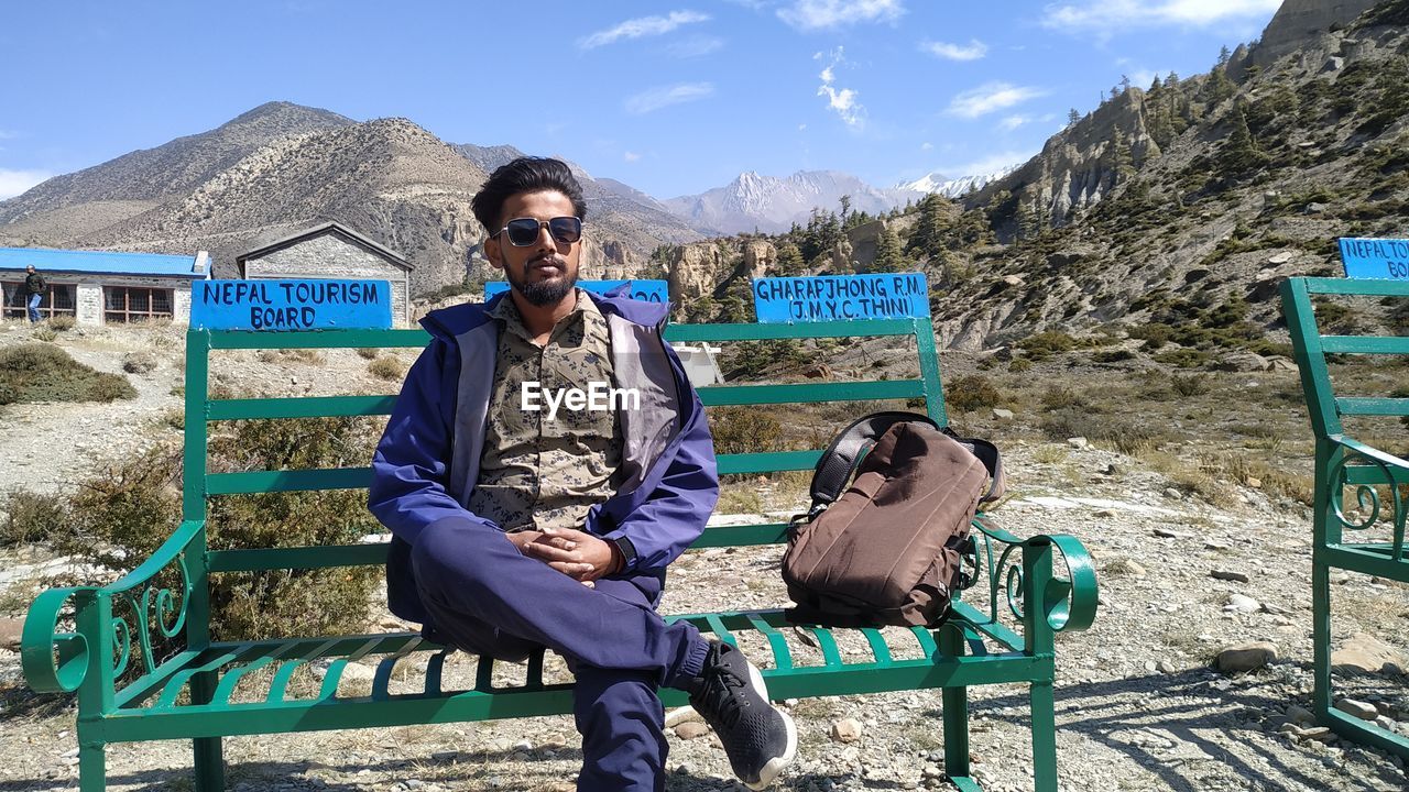 Full length portrait of young man sitting outdoors