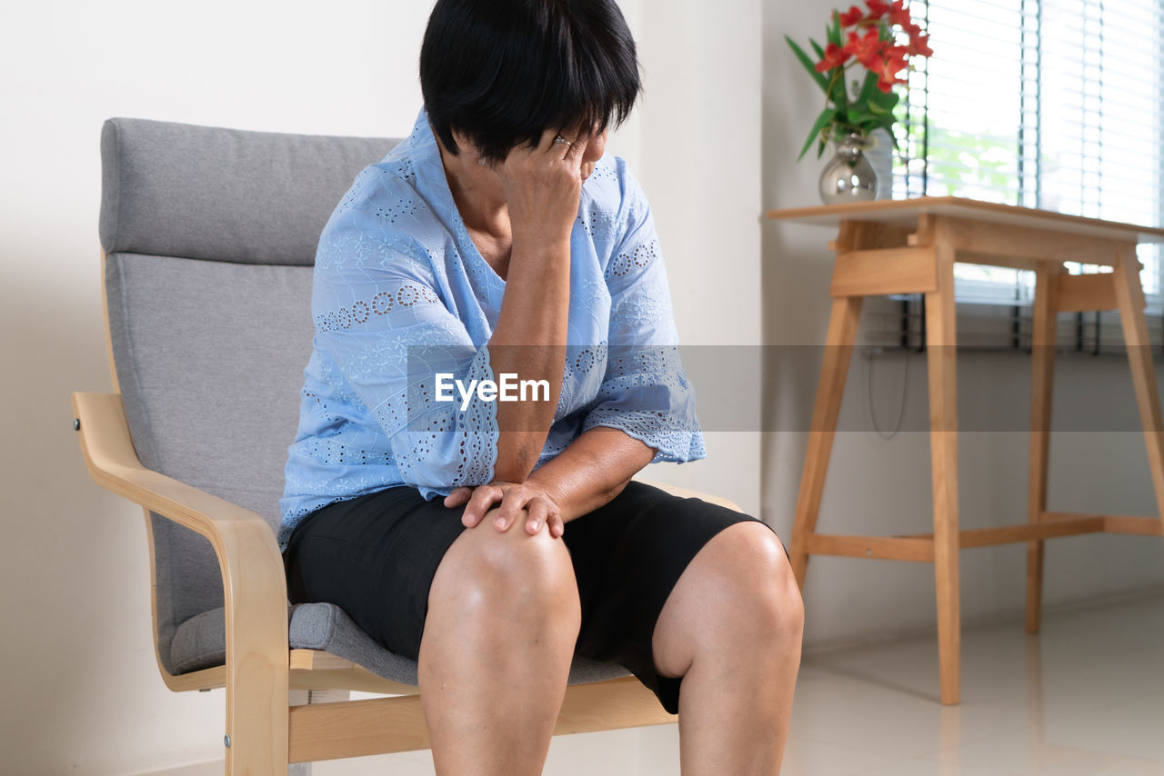 WOMAN SITTING ON CHAIR AT HOME