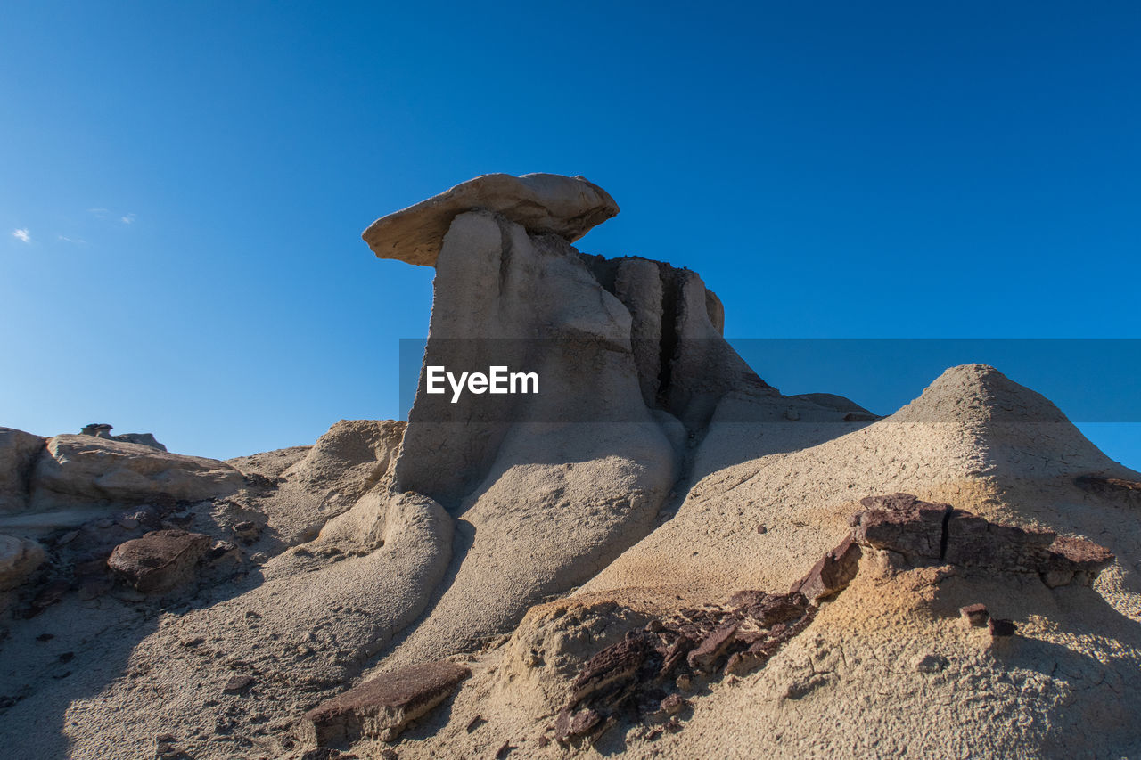 Bisti badlands landscape of dramatic grey hoodoos or caprock formations against blue sky 