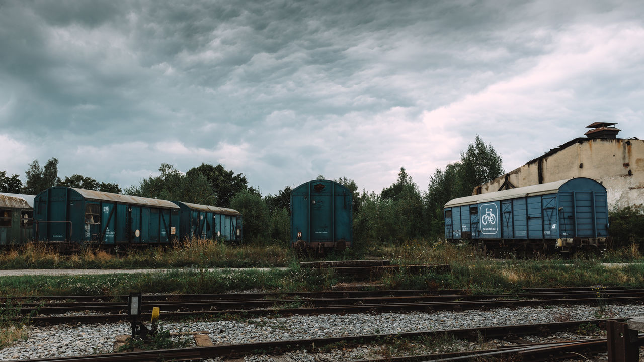 Railroad tracks by shunting yard against cloudy sky