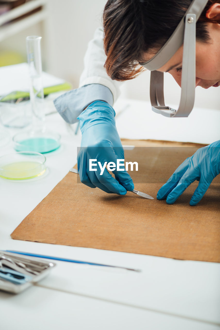 Professional conservator removing the dirt from reverse side of the antique oil painting canvas