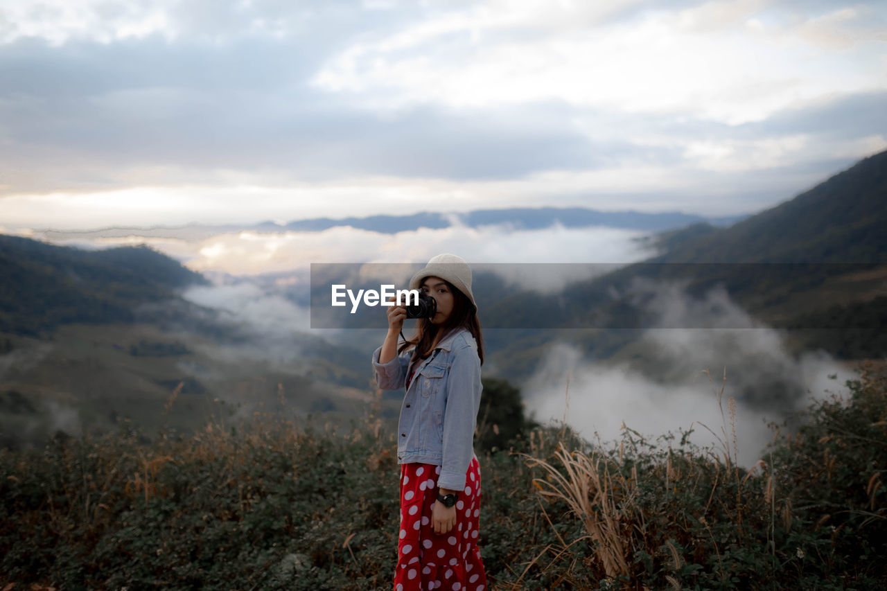 WOMAN STANDING AGAINST MOUNTAIN RANGE