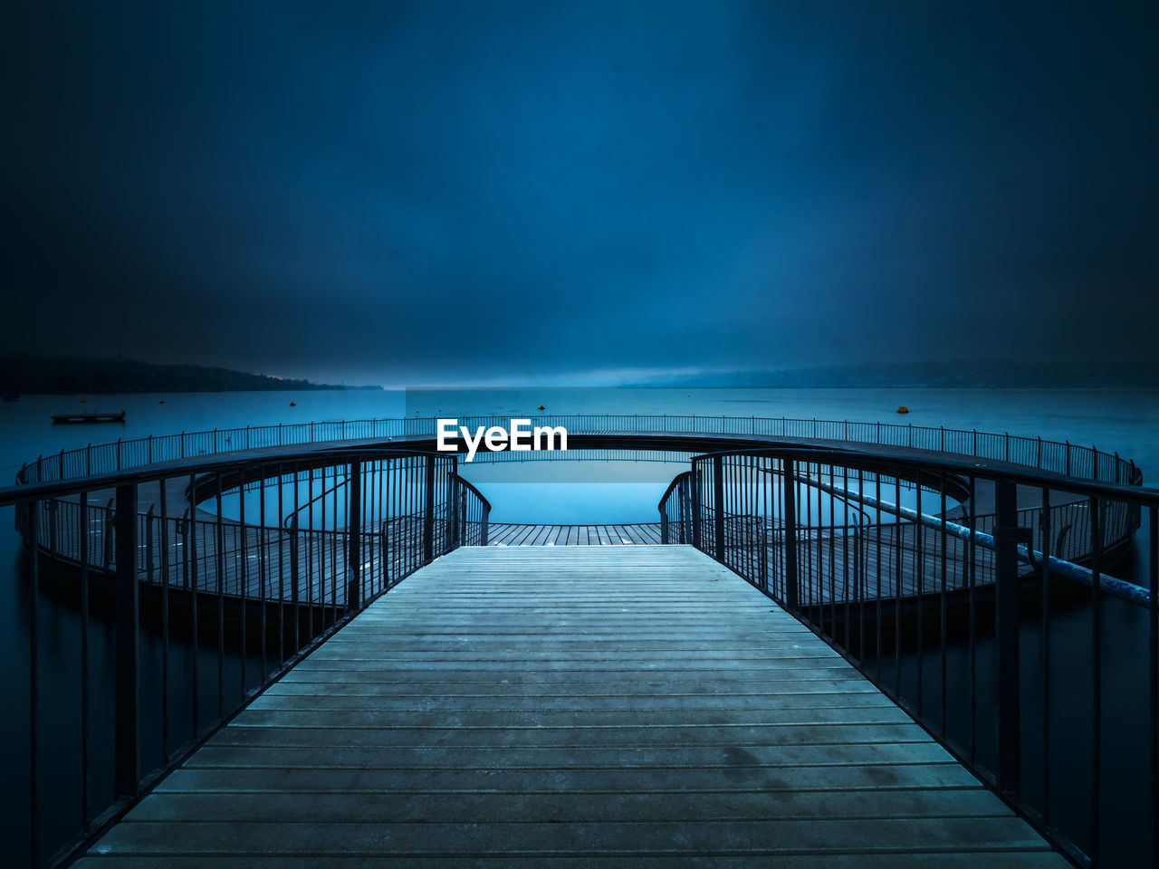 Footbridge over sea against sky at night