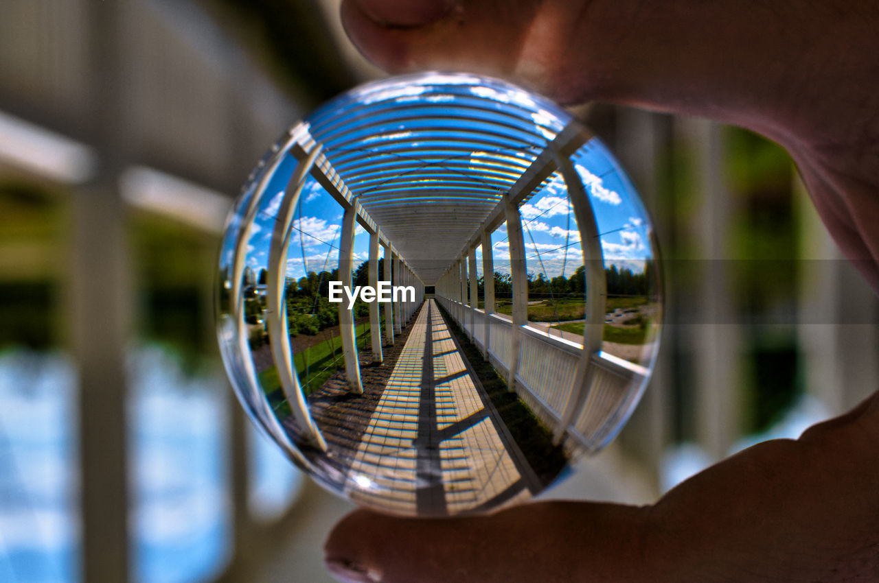 Cropped hand holding crystal ball with reflection of walkway