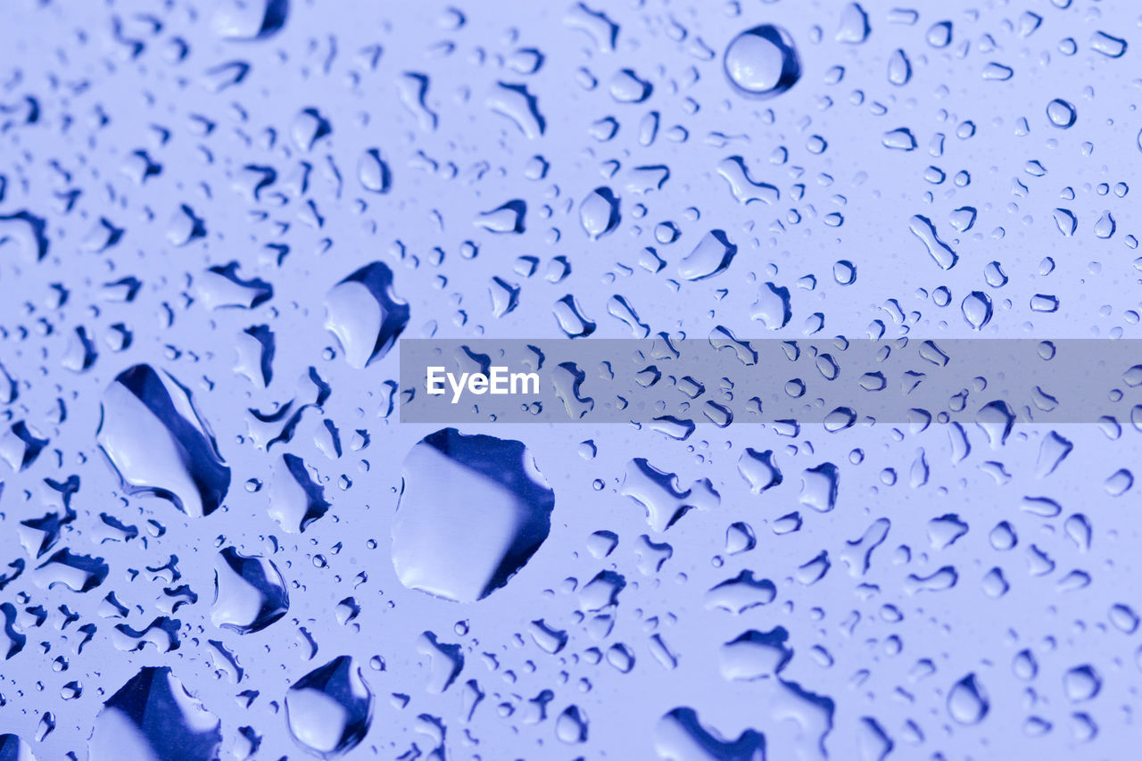 FULL FRAME SHOT OF WATER DROPS ON BLUE SURFACE