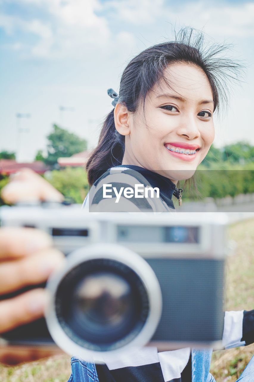 Portrait of a smiling young woman holding camera