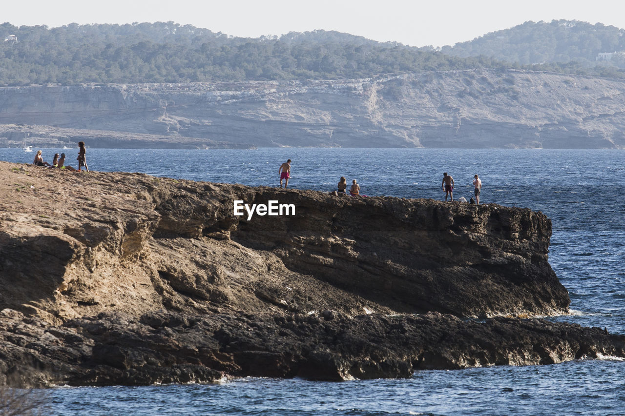 People on cliff by sea