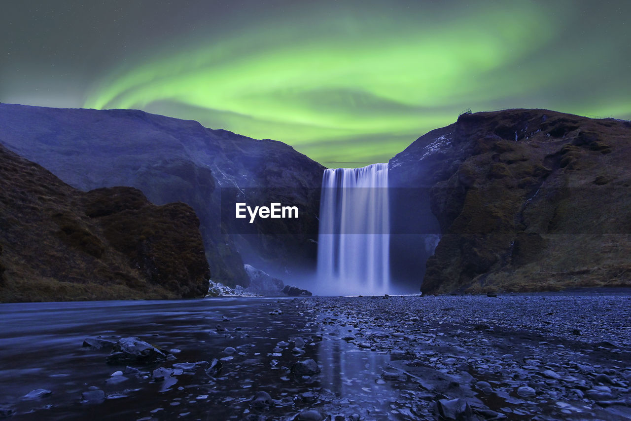 Flash of aurora polaris above skogafoss waterfall, iceland