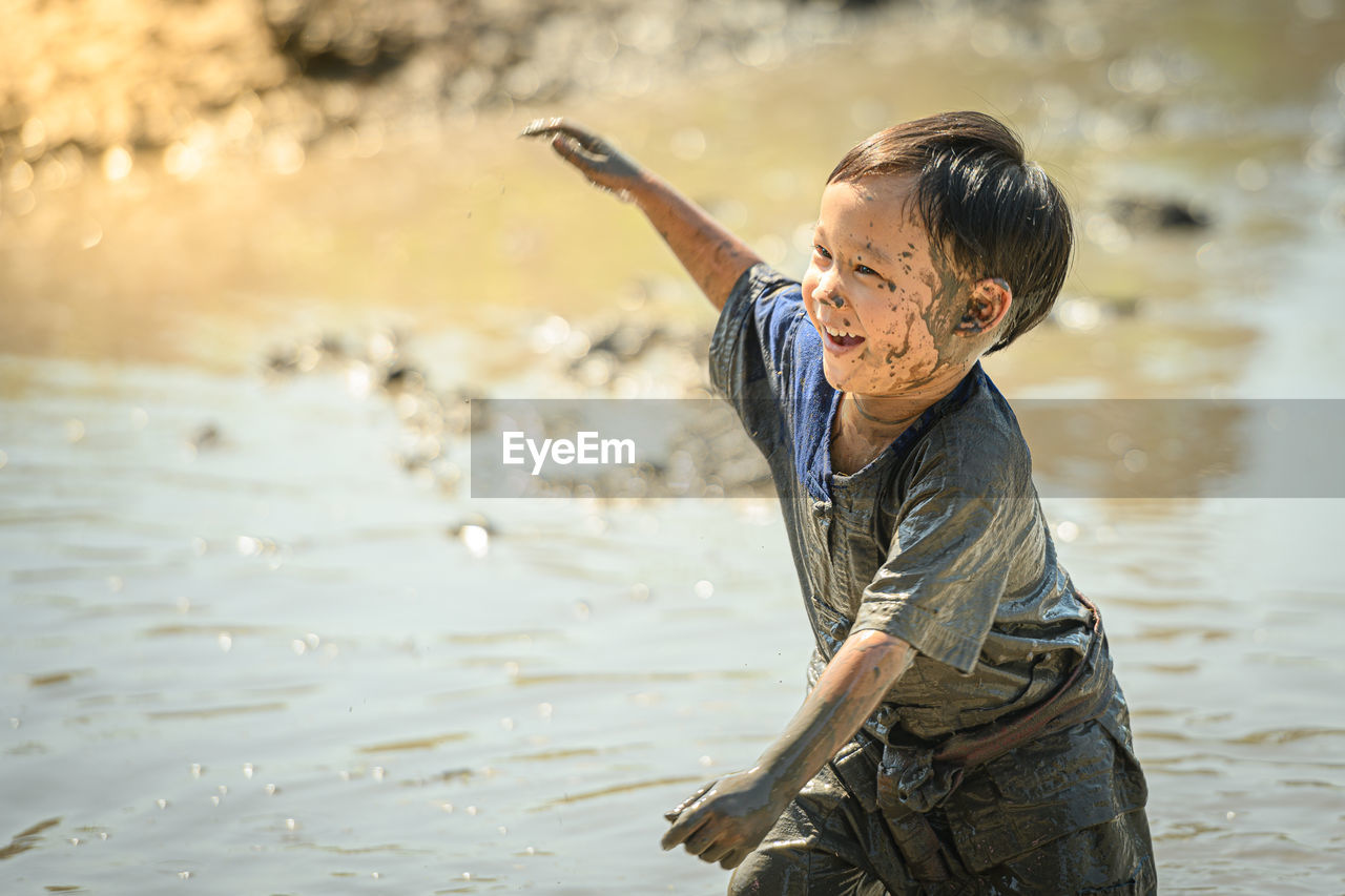 Smiling boy playing on mud outdoors