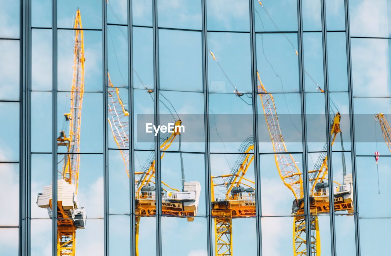 Reflection of cranes in modern glass building