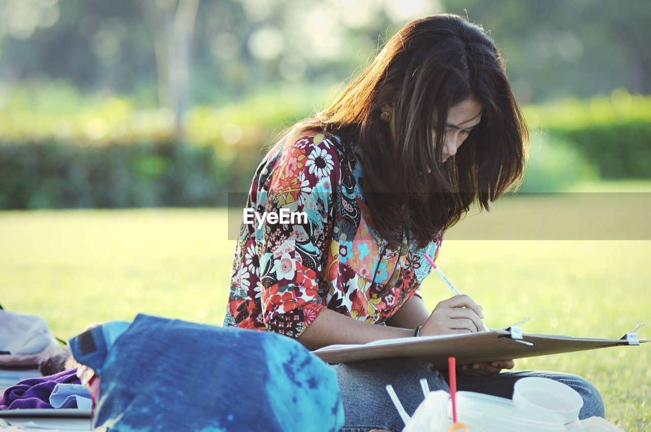 Young woman drawing while sitting at park