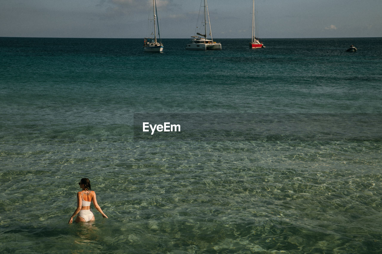 Rear view of woman in sea against sky