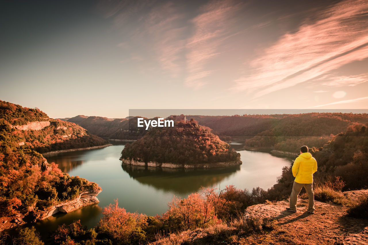 View of man standing by horseshoe bend in ter river and mountain with sant pere de casserres abbey