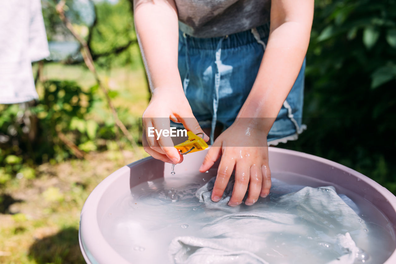 Little preschool girl helps with laundry. child washes clothes in garden