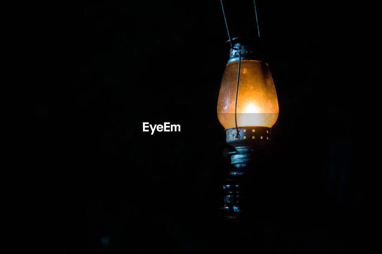 Close-up of lit lantern over black background