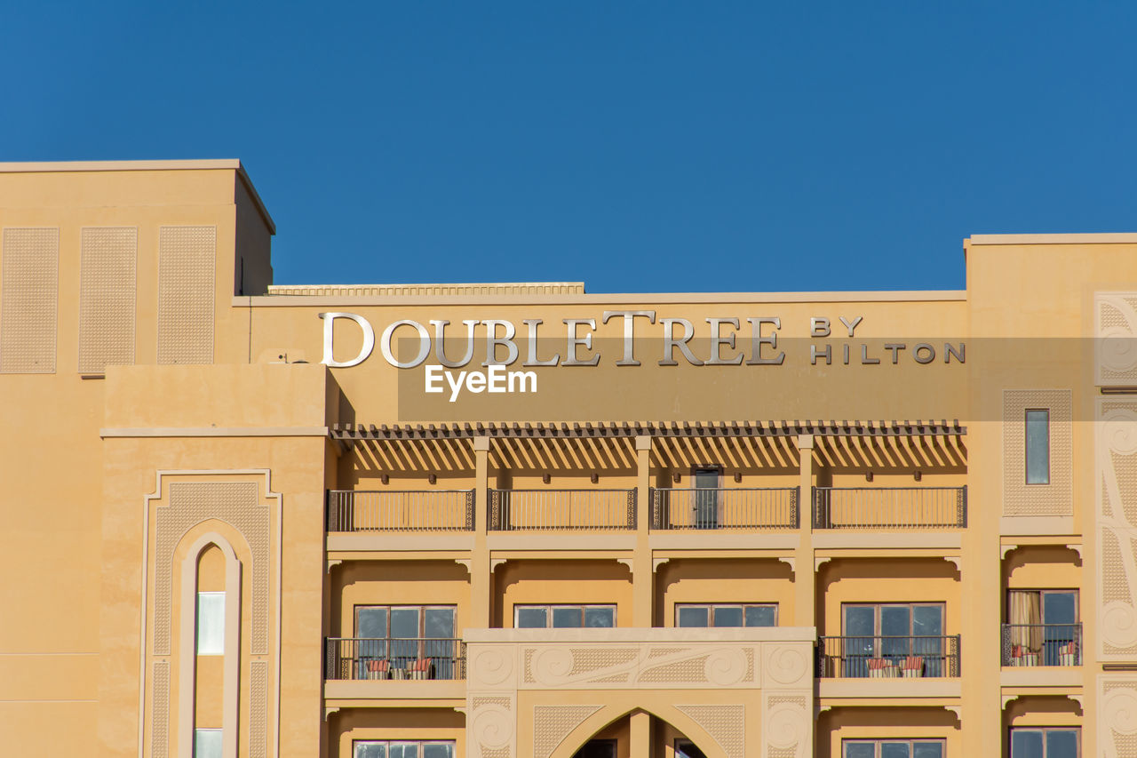 LOW ANGLE VIEW OF TEXT ON BUILDING AGAINST CLEAR SKY