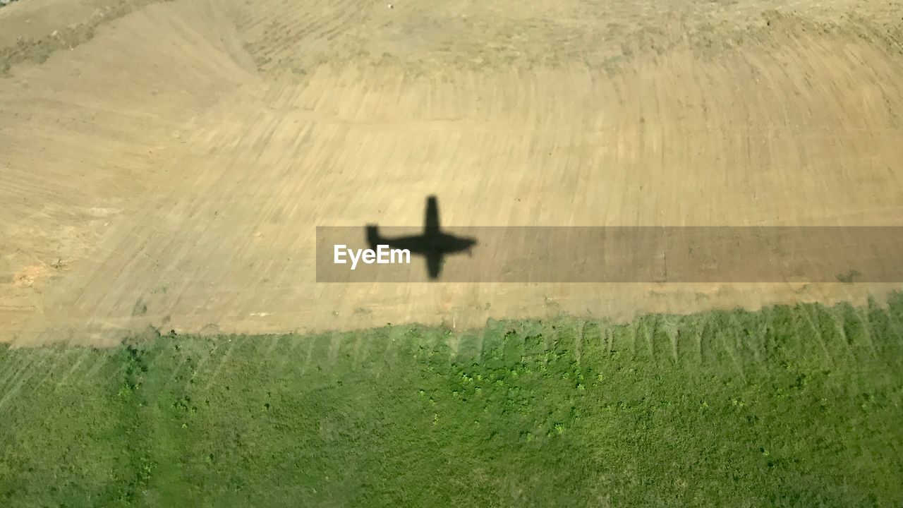 High angle view of shadow of an airplane on field