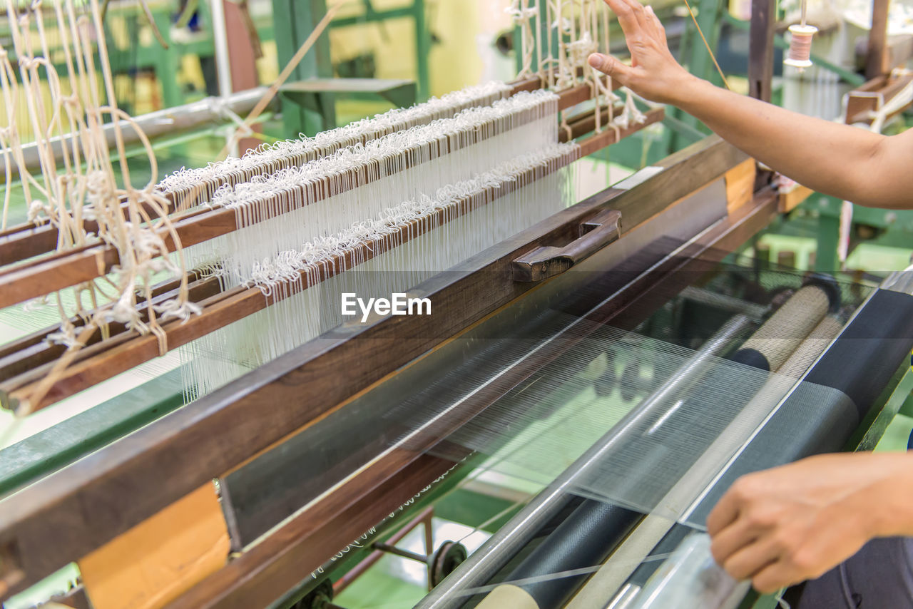 Cropped image of manual worker weaving thread in textile industry