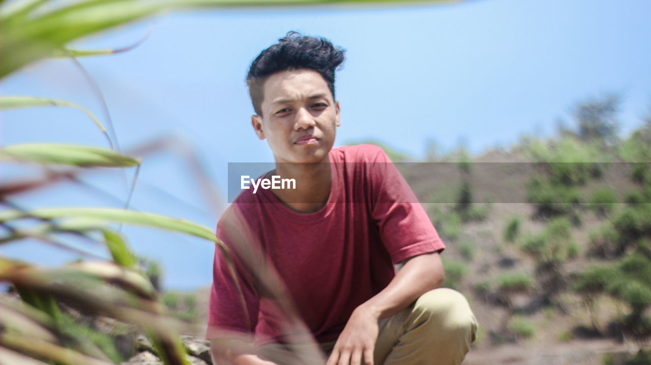 Portrait of young man crouching outdoors