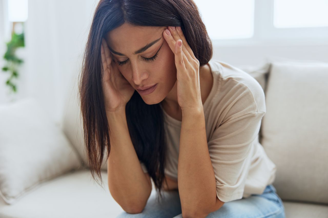 side view of young woman sitting on bed at home