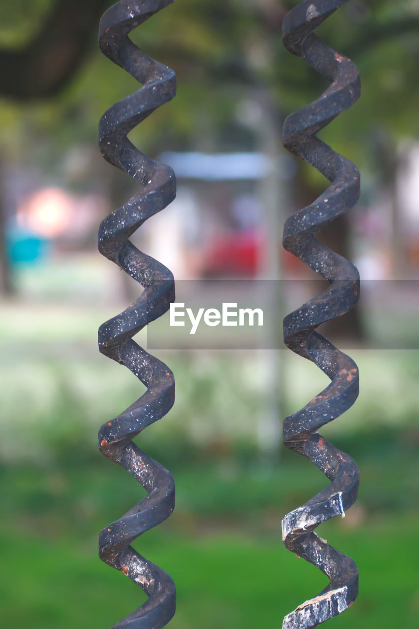 metal, no people, focus on foreground, green, close-up, fence, nature, day, outdoors, strength, plant, pattern, selective focus