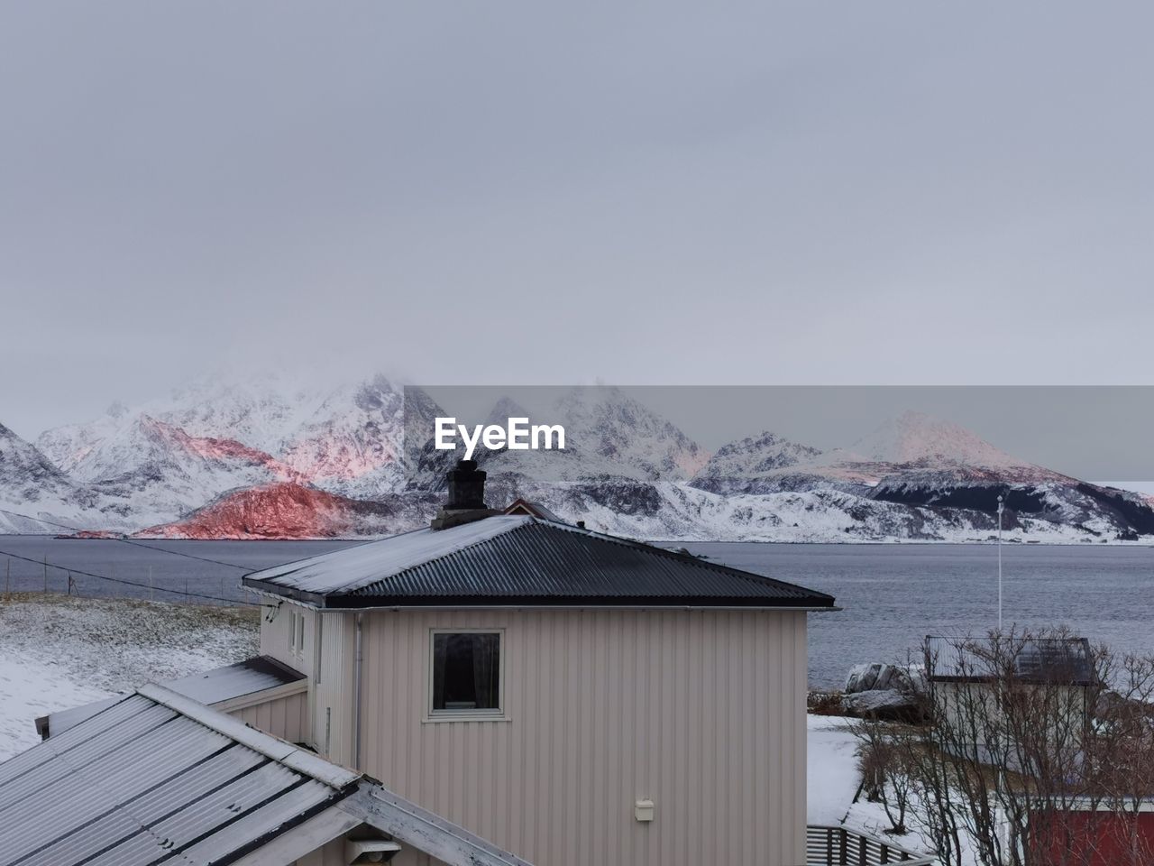 house by snowcapped mountains against clear sky