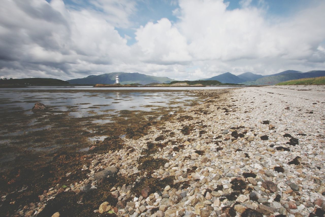 Scenic view of beach against cloudy sky