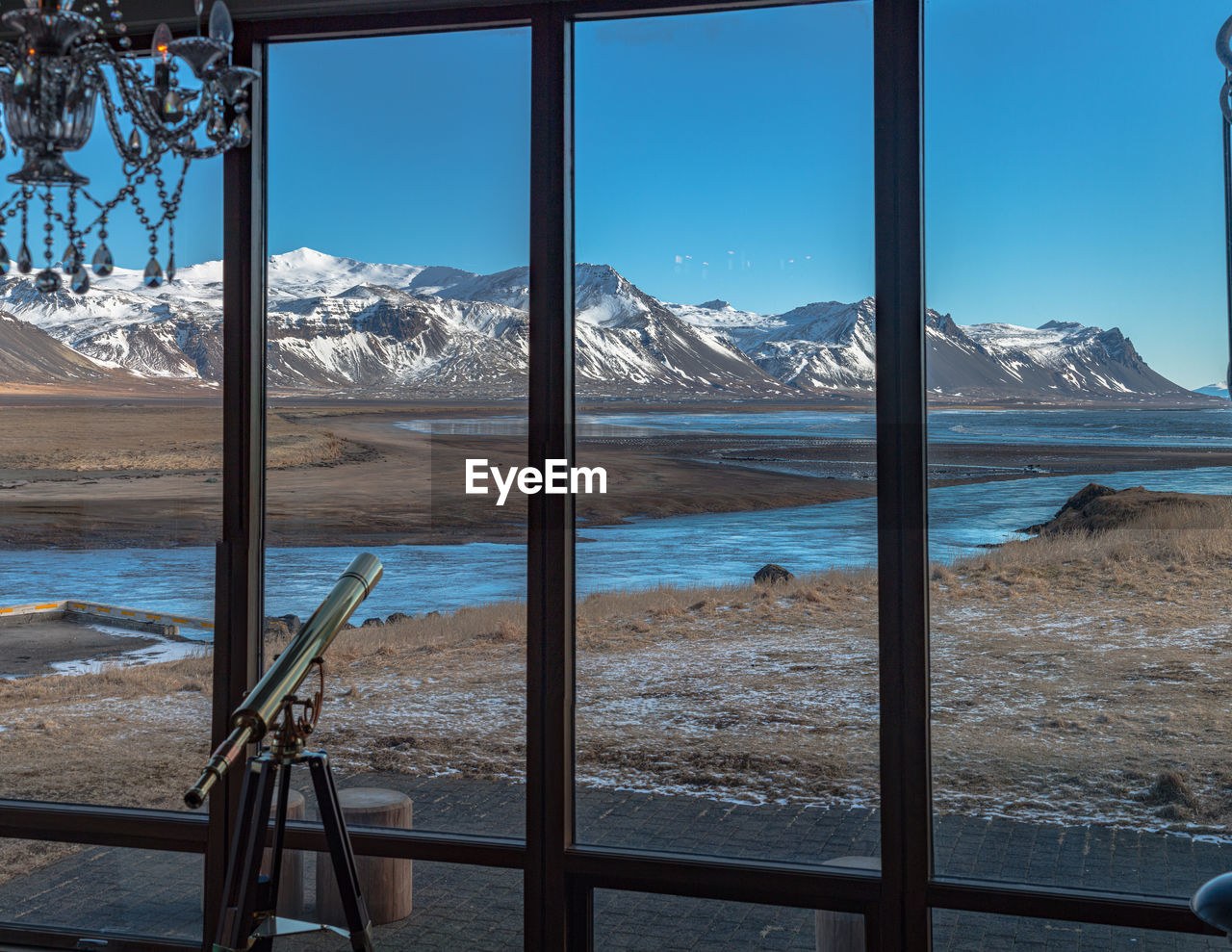 Panoramic view looking out windows on snow covered mountain range with an ocean bay