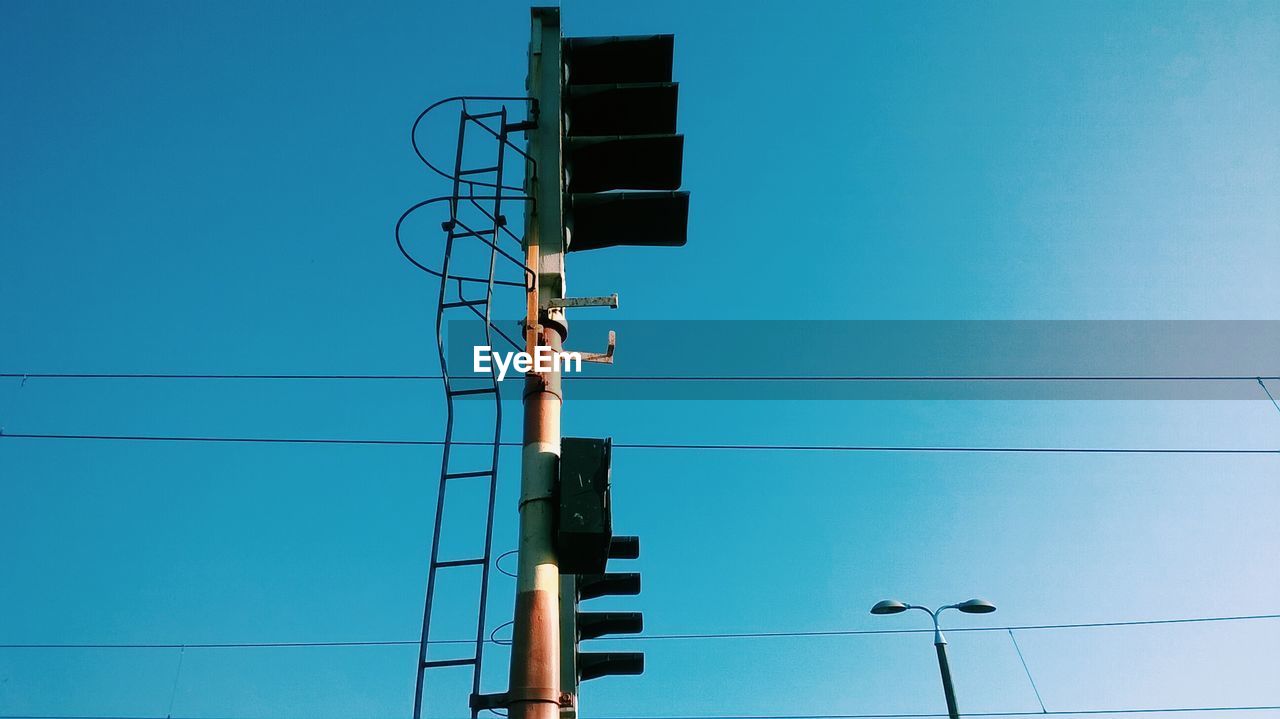 Low angle view of traffic light against clear blue sky