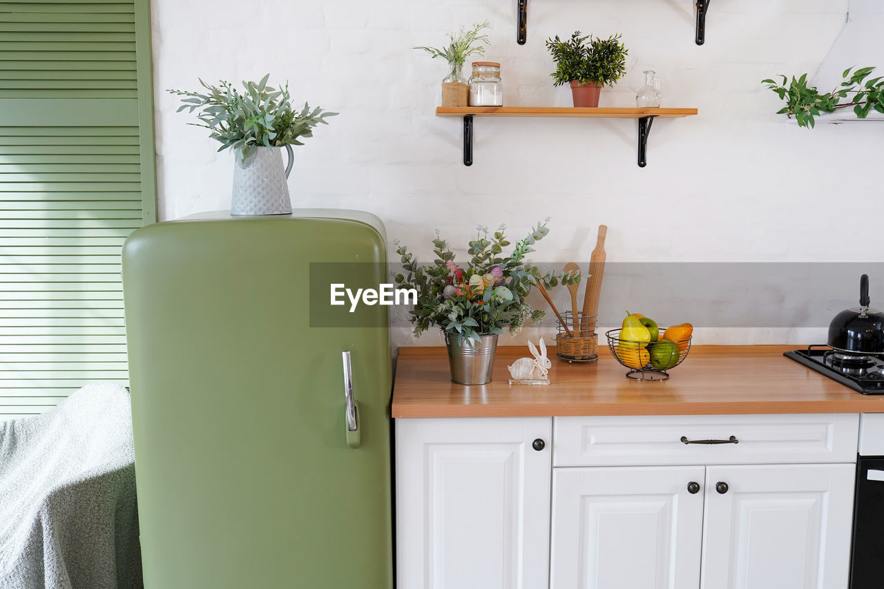 Easter eggs, flowers and rabbit on the table in a white scandinavian-style kitchen