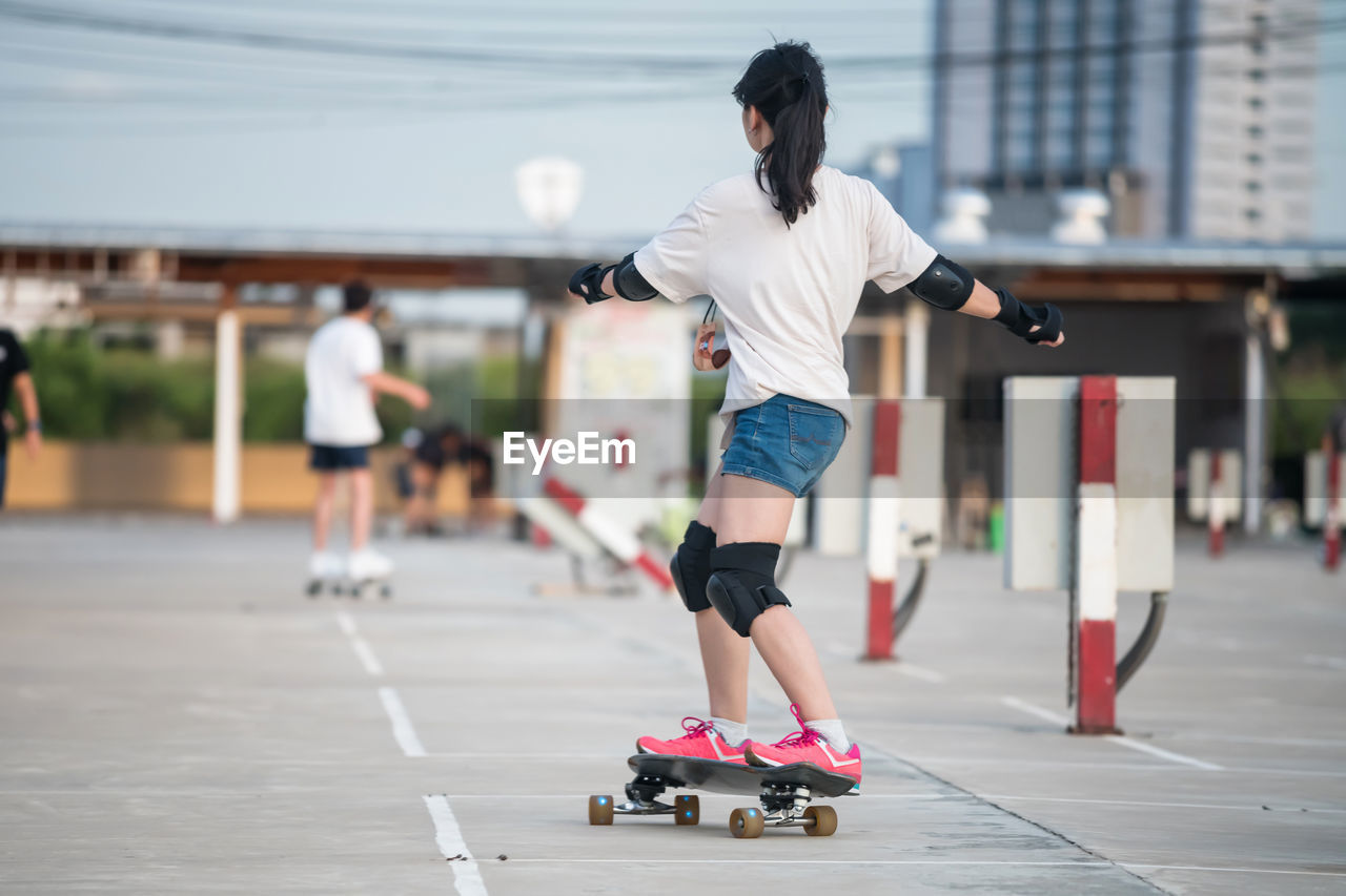 Asian female surfer with safety tools having fun with surfboards or surf skate around city 