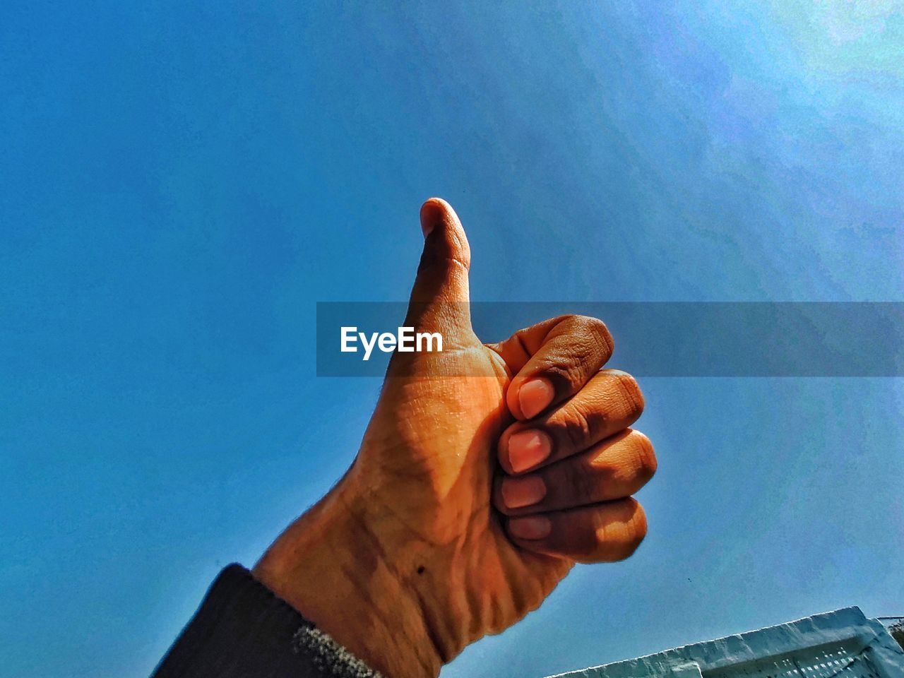 LOW ANGLE VIEW OF HUMAN HAND AGAINST BLUE SKY
