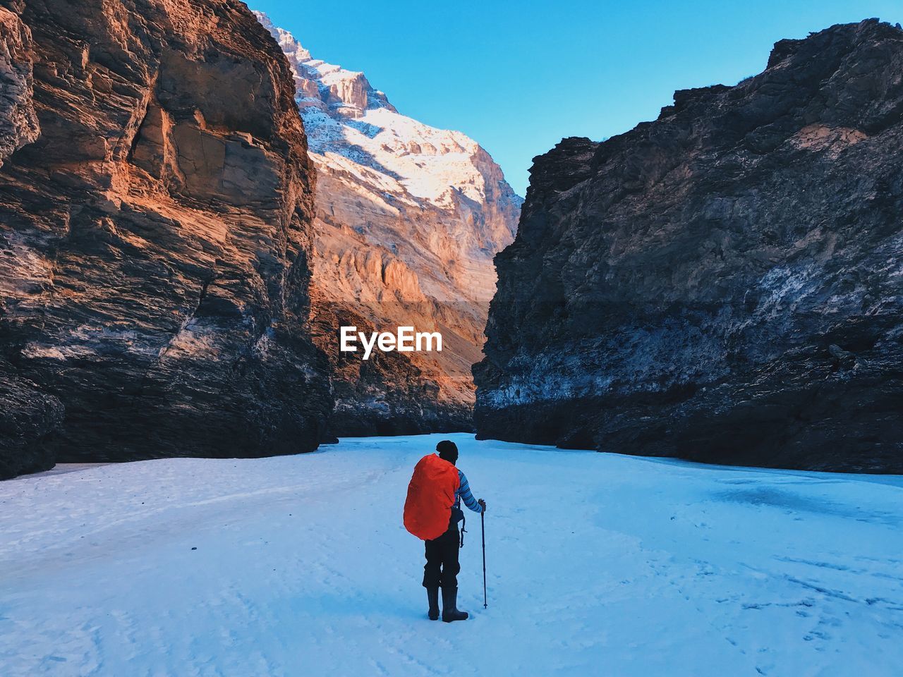 Rear view of man standing on snowy field against mountains