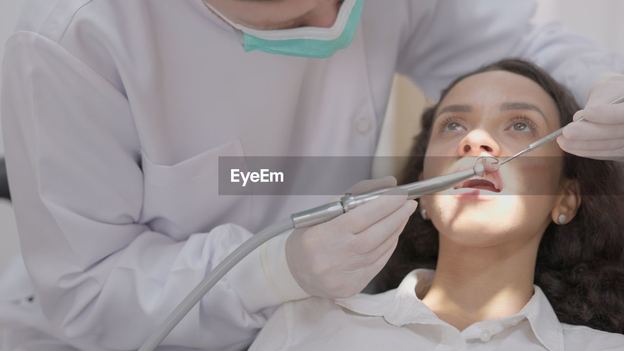 Midsection of dentist examining patient in clinic