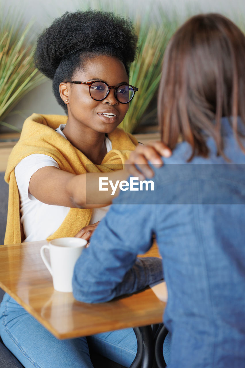 portrait of smiling friends sitting on table at home