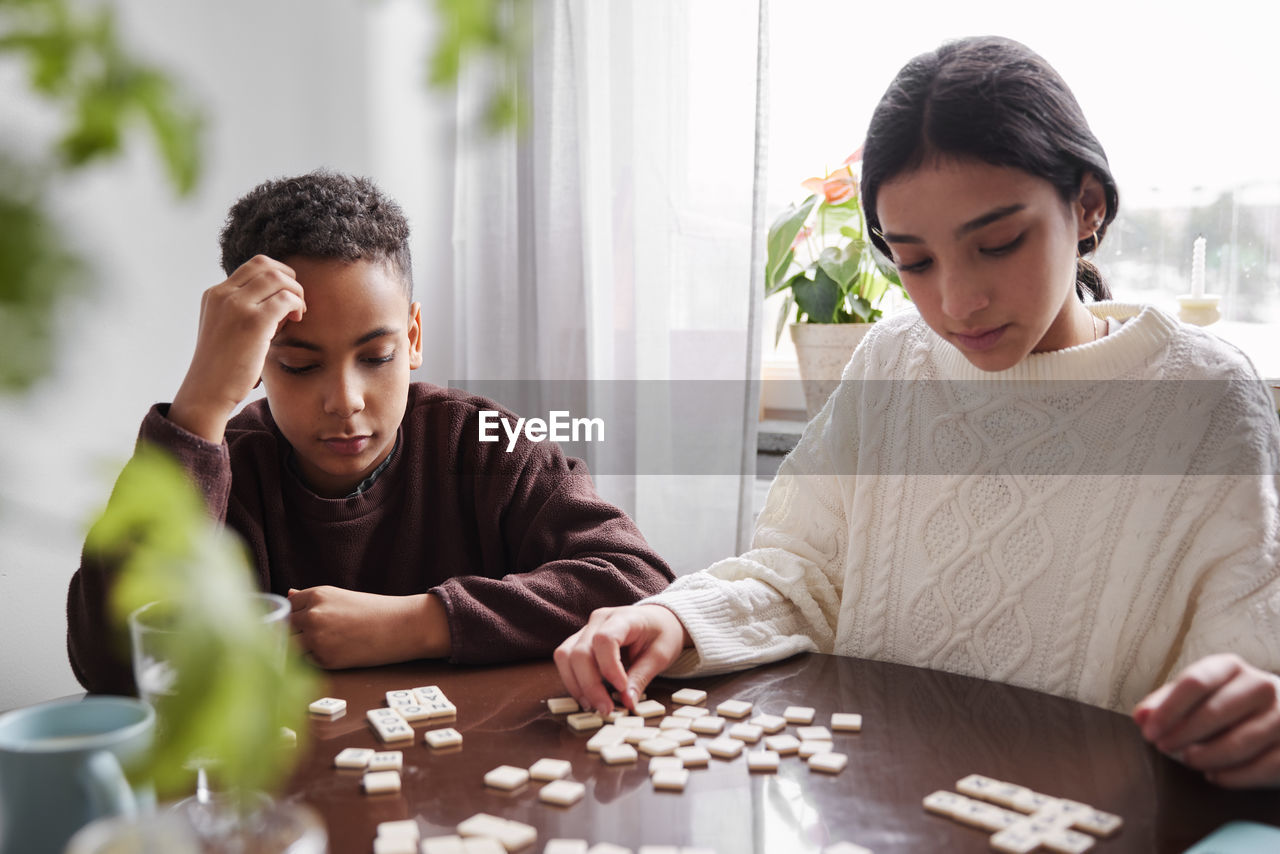 Girl and boy playing scrabble at dining table