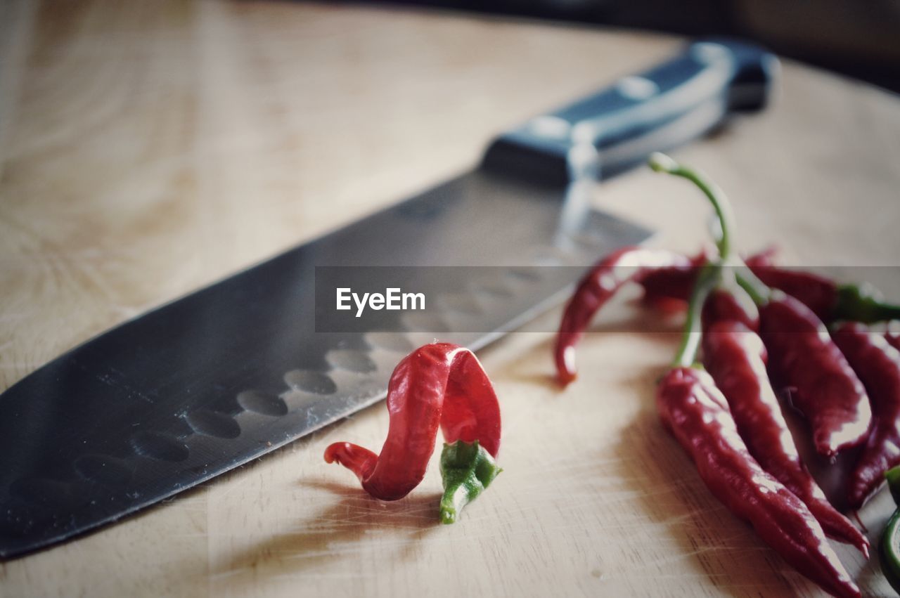 Red chili peppers with knife on cutting board in kitchen at home