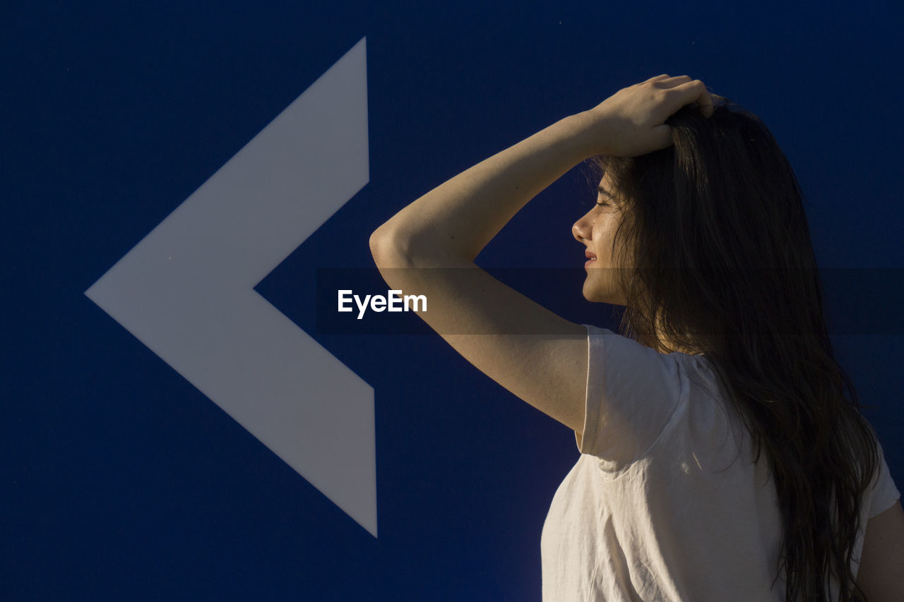 Side view of woman standing against blue wall