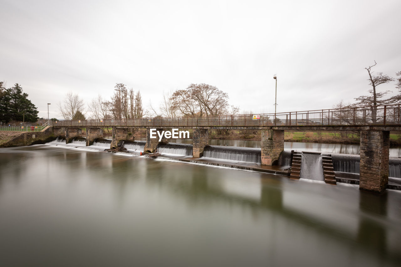 reflection, water, architecture, river, sky, built structure, bridge, nature, tree, morning, waterway, no people, cloud, environment, travel destinations, plant, outdoors, building exterior, winter, travel, day, overcast, transportation, tranquility, city