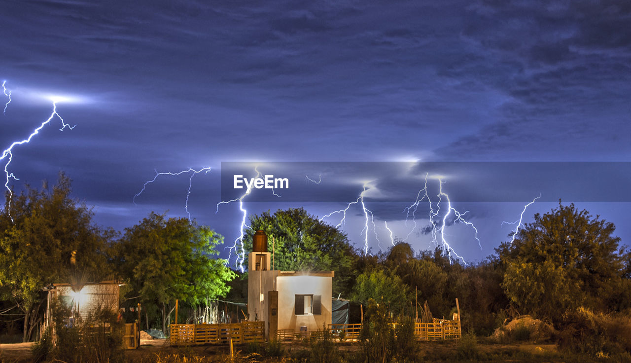 LIGHTNING OVER ILLUMINATED BUILDING AGAINST SKY