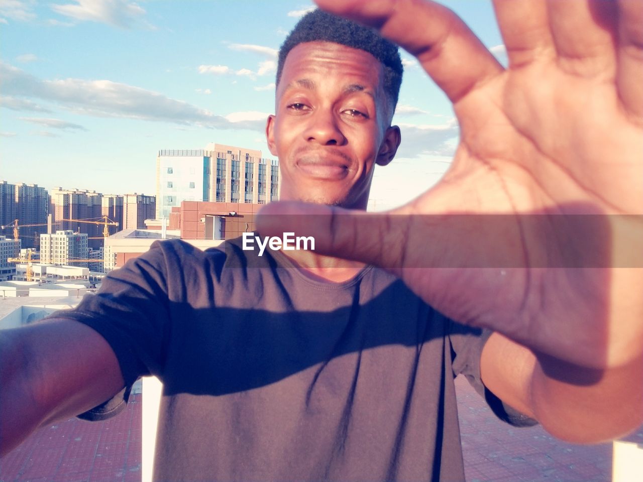 Portrait of smiling man gesturing while standing in city