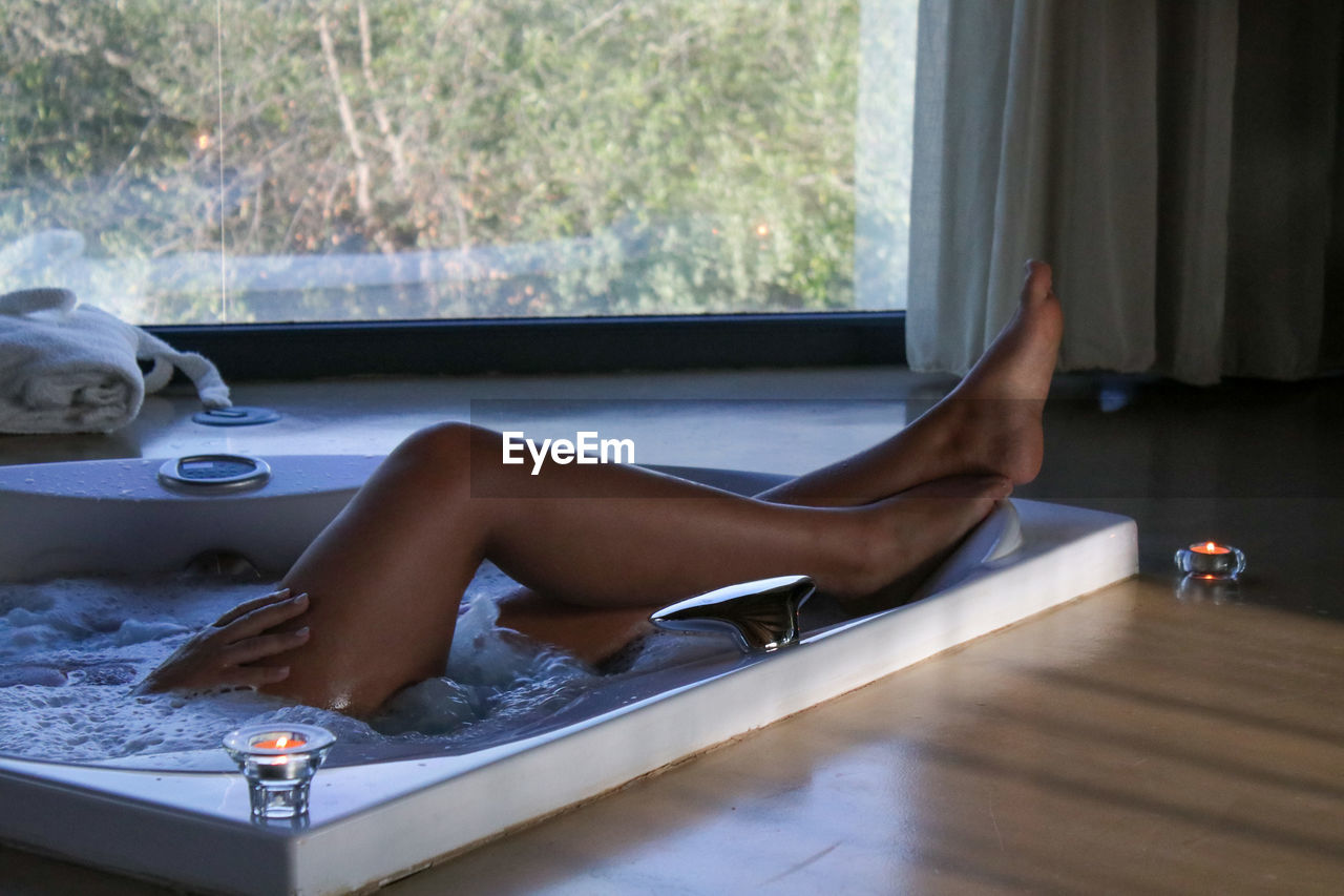 Low section of woman relaxing in bathroom