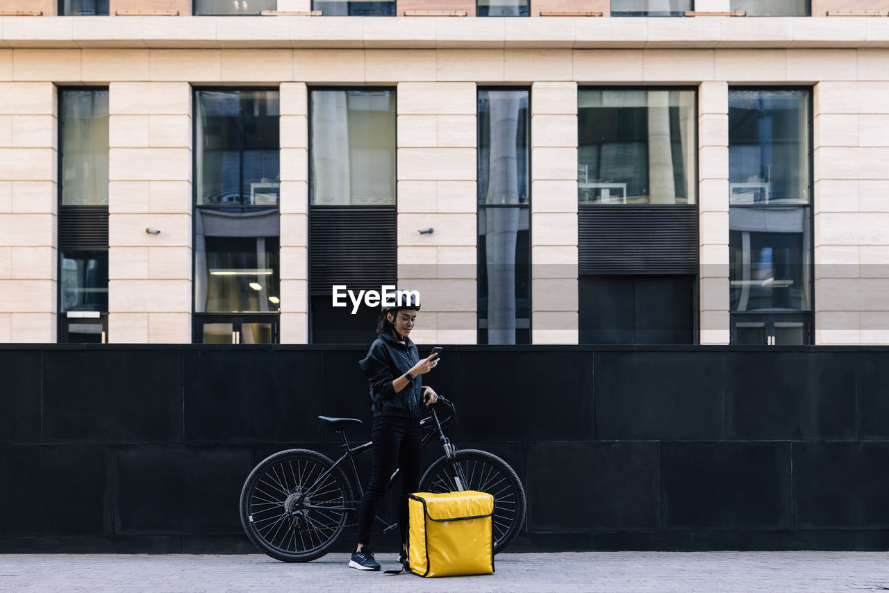 Delivery person using mobile phone by bicycle