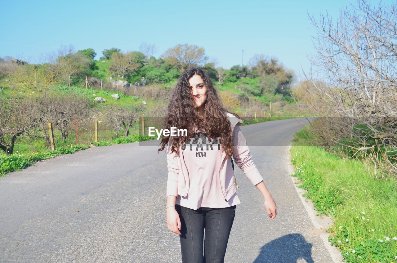 PORTRAIT OF WOMAN STANDING ON ROAD