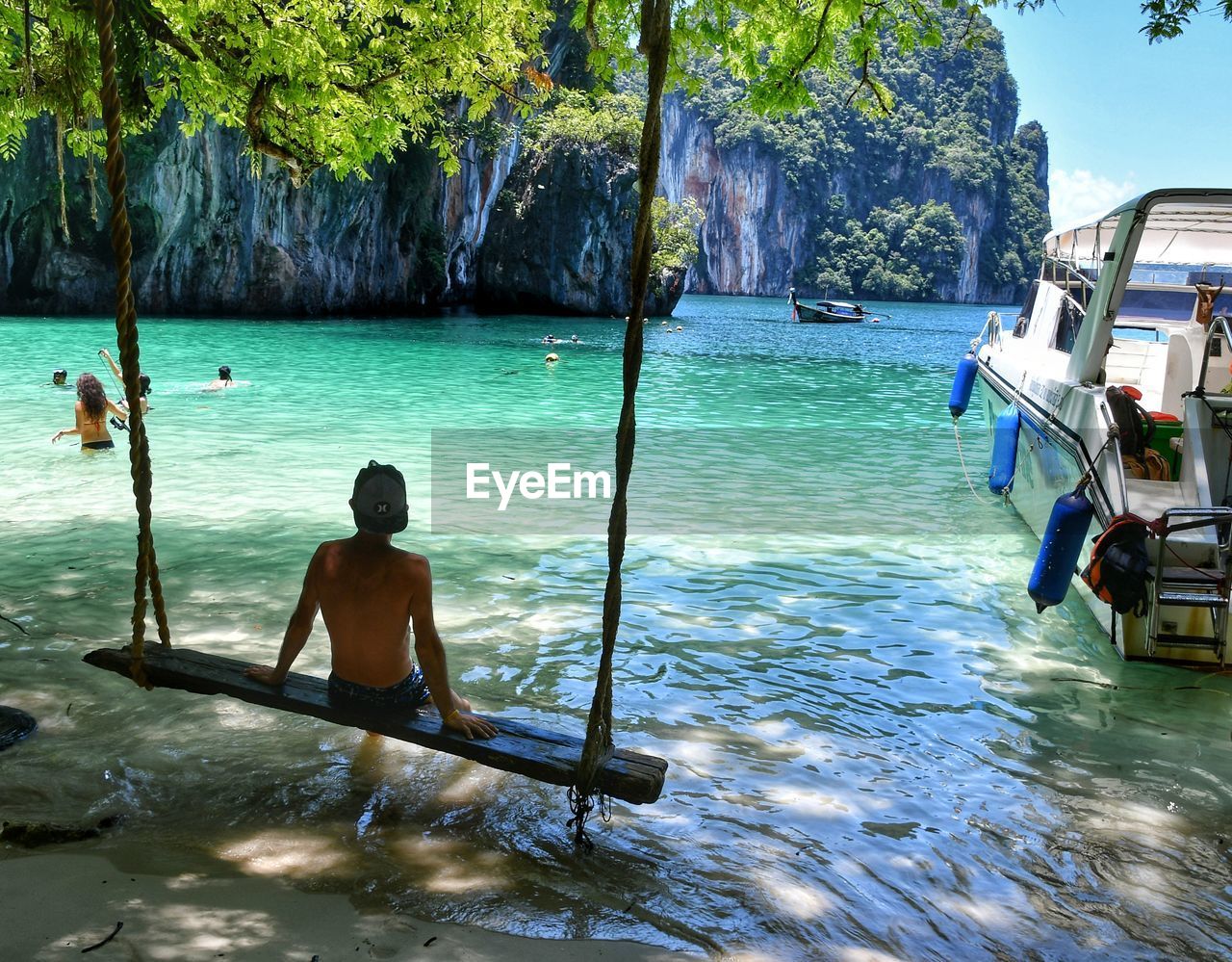 MEN SWIMMING IN SEA AGAINST SKY